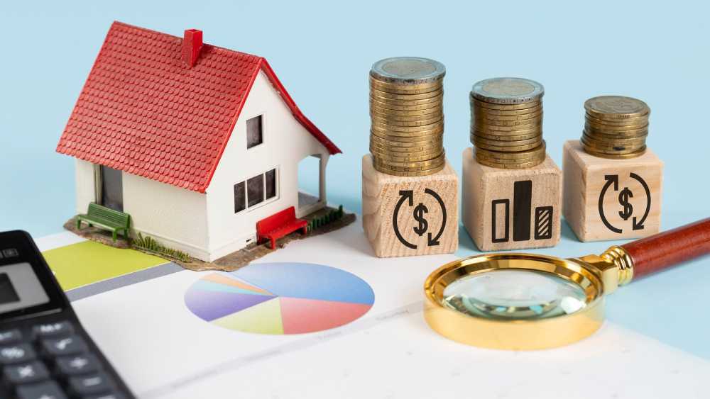 A model house, stacks of coins, and wooden blocks with finance icons on a graph paper, symbolizing real estate investment and analysis.