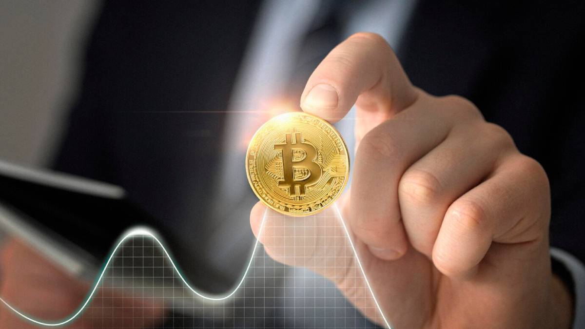 A business professional holds a glowing Bitcoi n above a financial graph, symbolizing cryptocurrency investment and market trends.