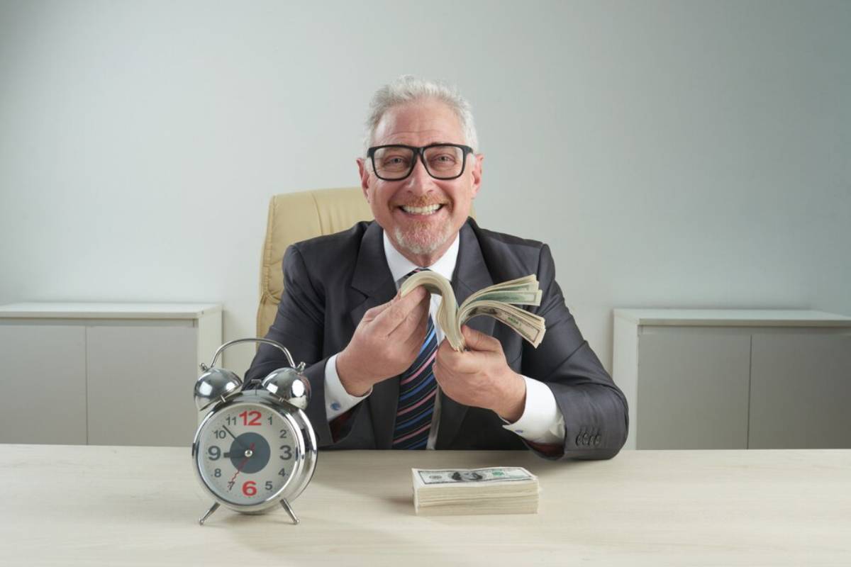 A businessman in a suit is counting cash at a desk, with a vintage clock beside him, reflecting a sense of urgency and finance.