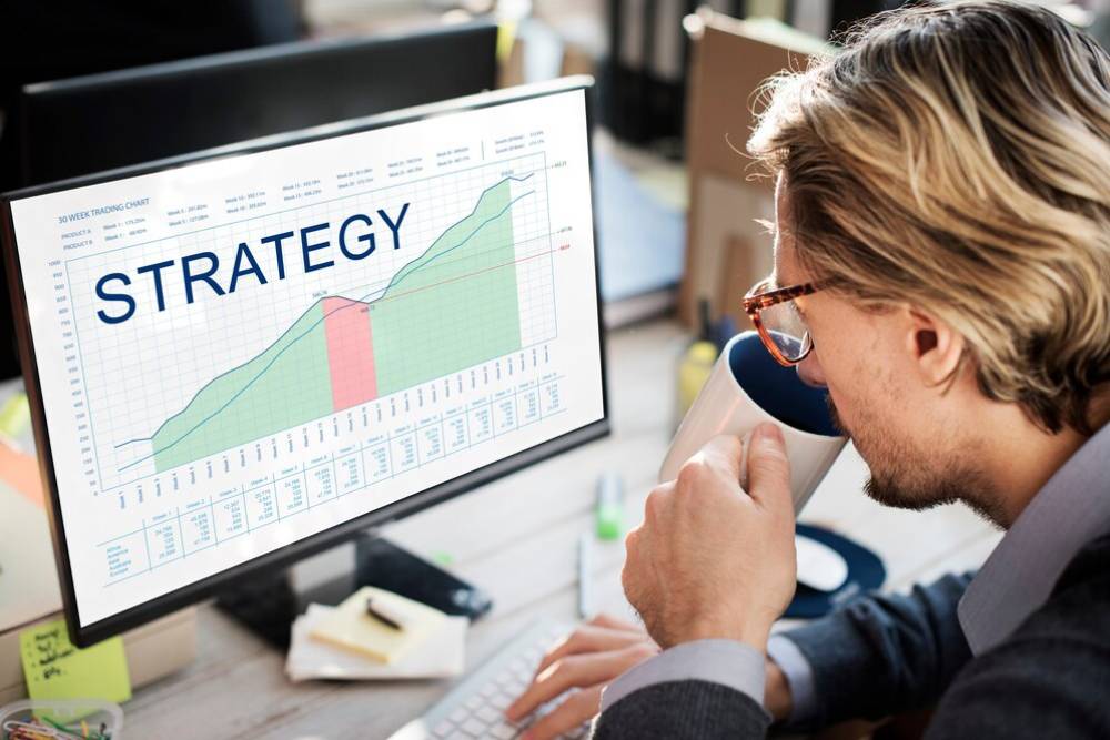 A person analyzing a trading chart on a computer screen, with graphs titled