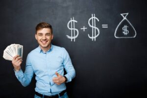 A person in a blue shirt holds cash in one hand, standing in front of a blackboard with dollar signs and a money bag illustration.