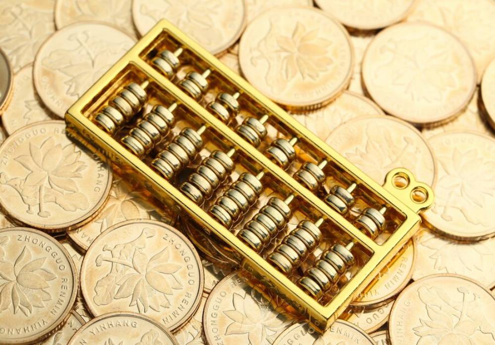 A golden abacus rests atop a bed of shiny gold coins, symbolizing wealth and traditional calculation methods.