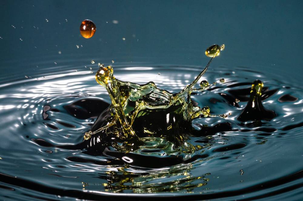 An splash of oil creating vibrant ripples against a dark background, capturing dynamic motion and light reflections.