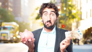 A man in a suit holds a piggy bank in one hand and cash in the other, set against a vibrant city backdrop.
