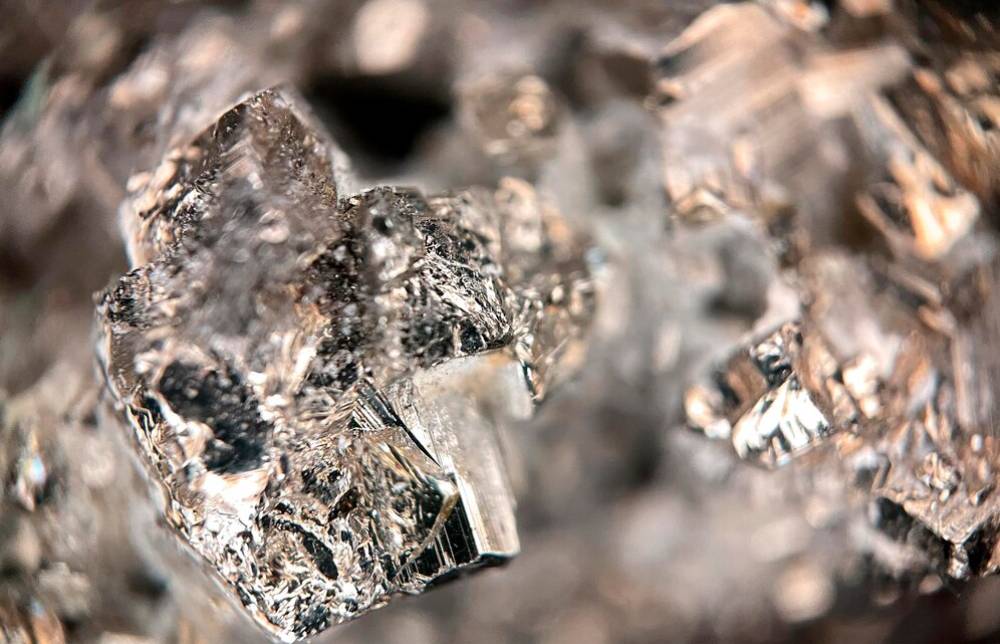 Close-up of sparkling, crystalline mineral formations, showcasing intricate facets and textures in clear, reflective surfaces.