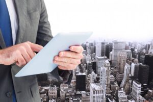A businessman in a suit using a tablet, with a panoramic view of a city skyline in the background, conveying a modern business vibe.
