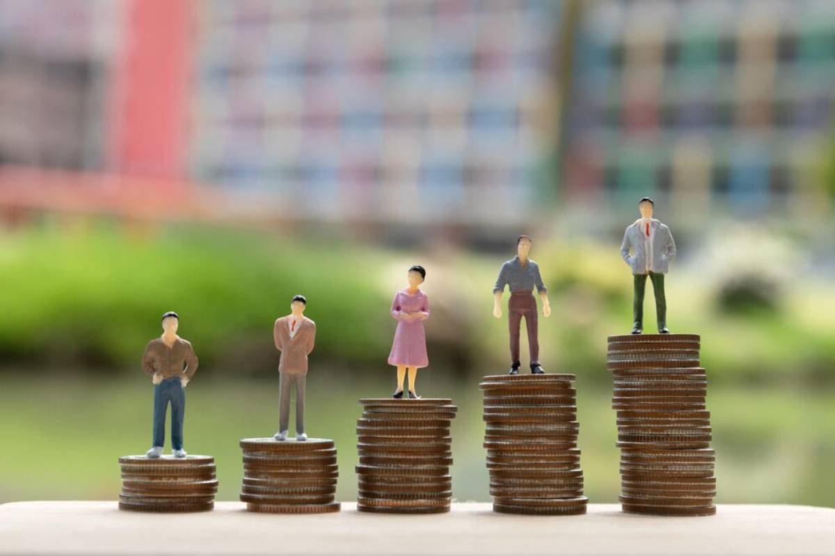Miniature figurines stand atop stacks of coins, representing financial growth and progress in a vibrant outdoor setting.