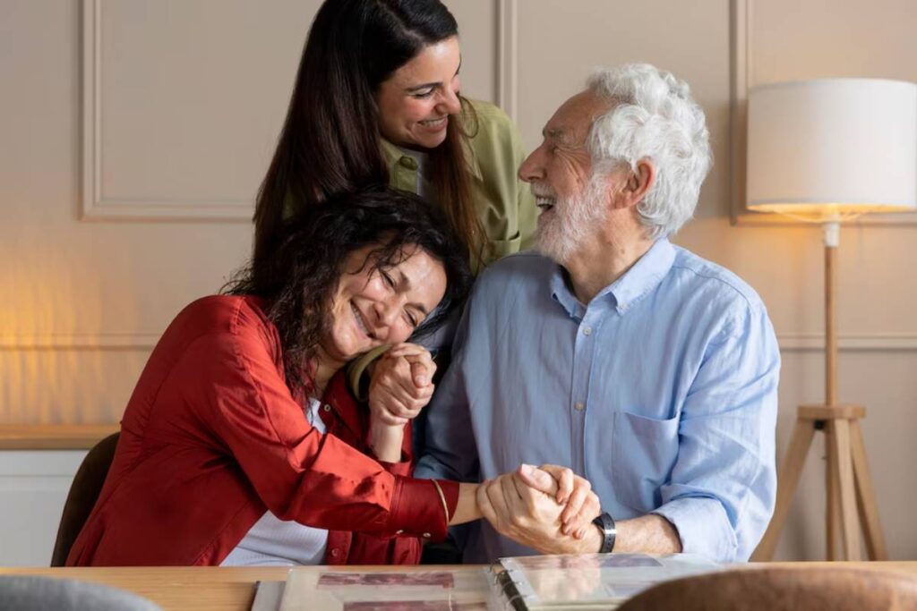 A group of three people shares an intimate moment, holding hands together around a table with family photos displayed.
