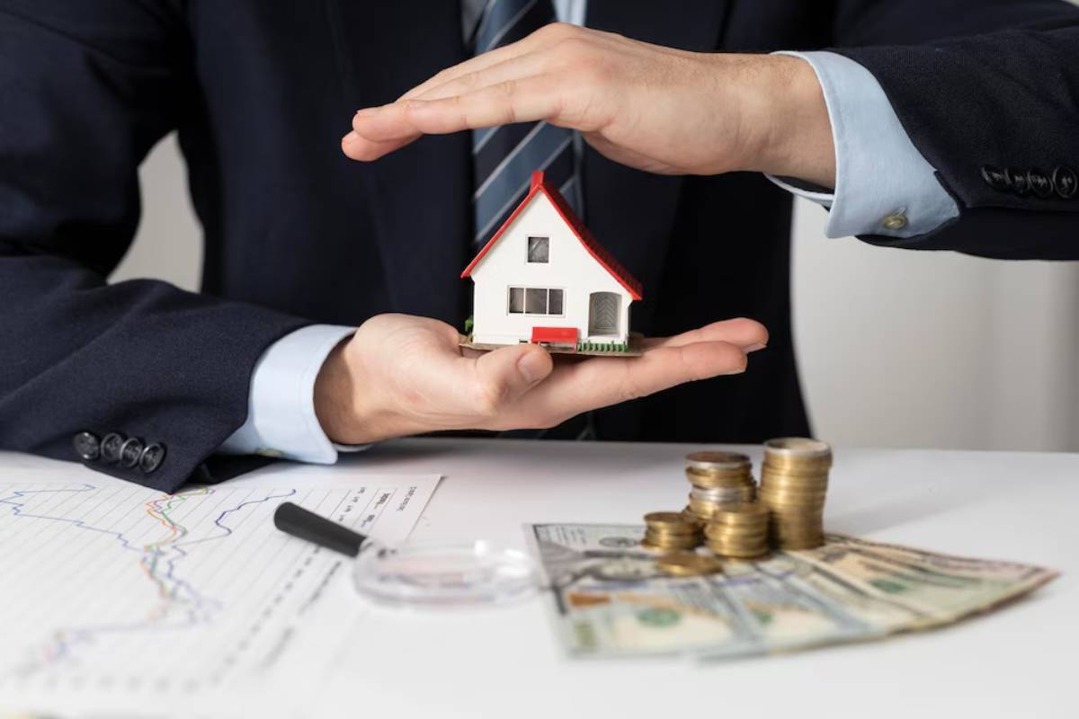 A businessman in a suit gently holds a small house model, surrounded by money and charts, symbolizing property investment security.